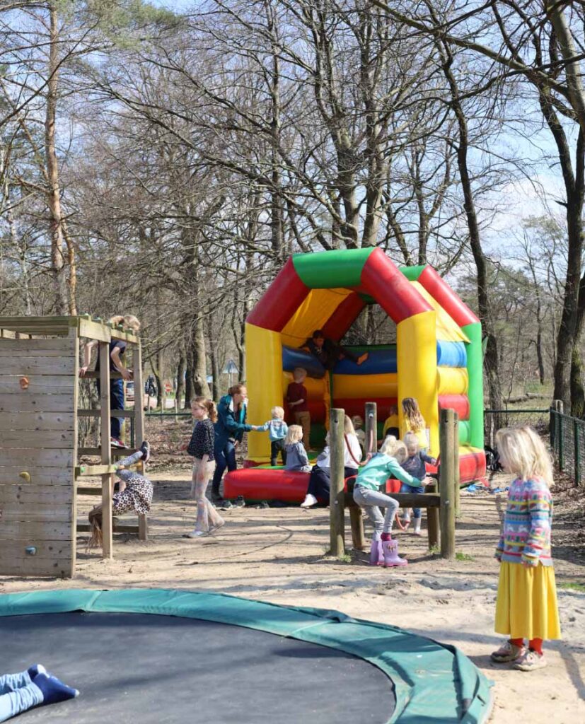 Spelende kinderen in de speeltuin bij de Zweef met het springkussen, trampoline en klimrek